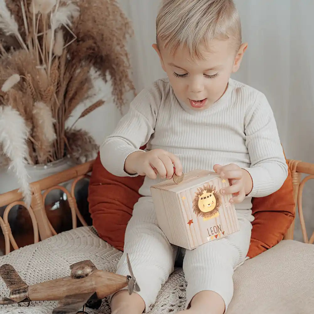Enfant glissant une pièce dans sa tirelire personnalisée, motif lion couronné — Kidsmood